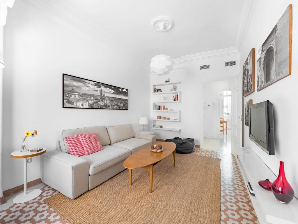 A cozy living room with a light grey sofa, patterned cushions, a woven rug, and minimal decor, showcasing an easy approach to incorporating patterns in small spaces.