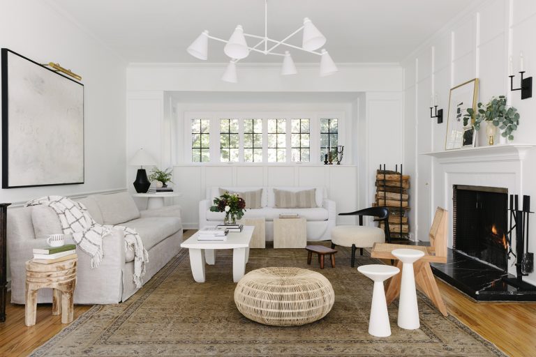  A modern living room showcasing sculptural furniture with a balance of neutral tones and natural light, including a mix of textured elements like a woven ottoman, sleek tables, and artistic wooden chairs.
