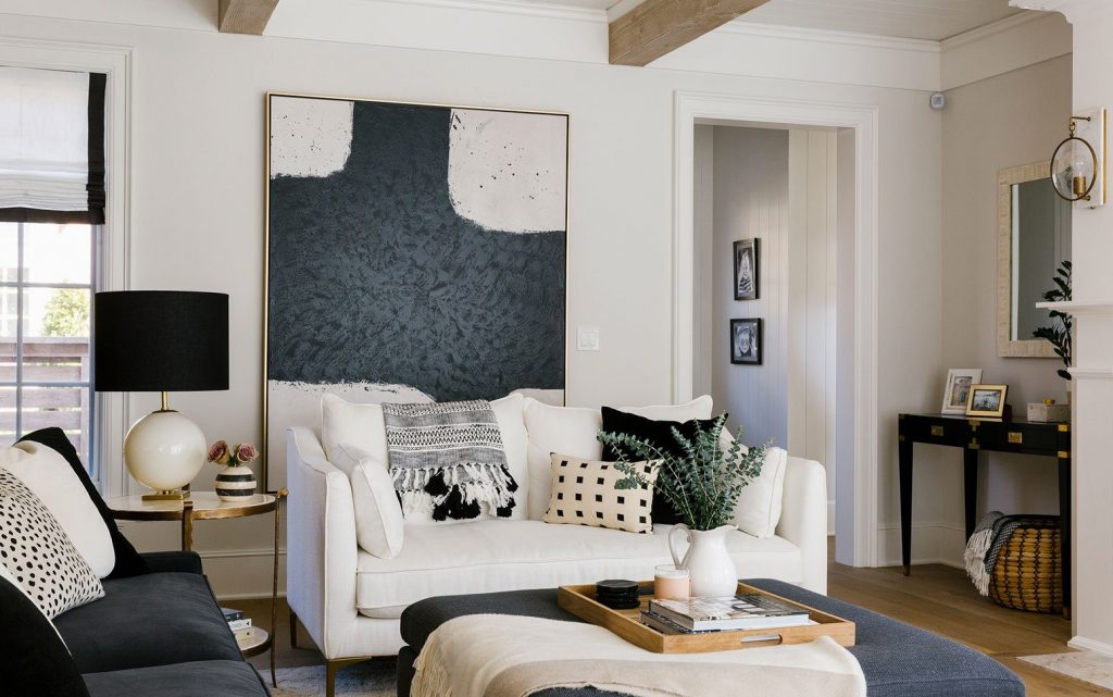 A modern living room featuring oversized abstract wall art as the focal point, 
complemented by neutral-toned furniture, patterned cushions, and cozy decorative accents.